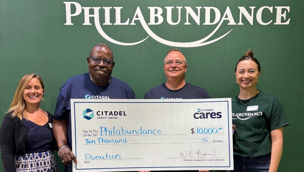 Two male bank executives present a giant check to nonprofit officials.