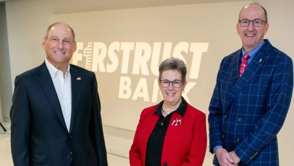 Bank's leadership team poses for picture in front of bank signage.