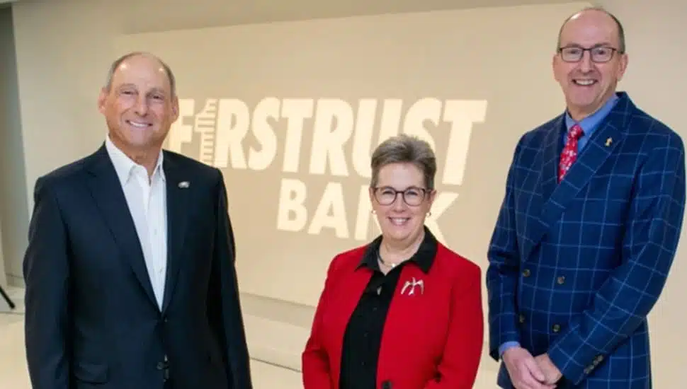 Bank's leadership team poses for picture in front of bank signage.