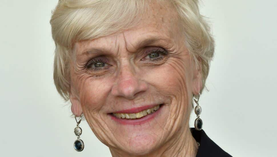 Portrait of Dr. Joy Dickerson, smiling, with short blonde hair, wearing black earrings and a dark blazer.