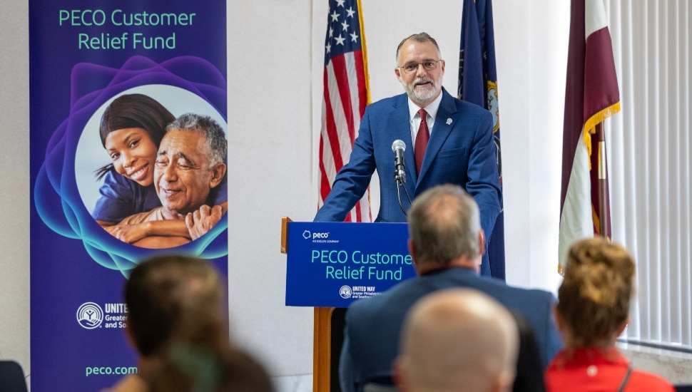 Middle-aged man in blue suit addresses the media at a press conference.