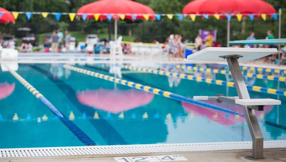 A sswimming pool with marked lanes and a patio with umbrellas.