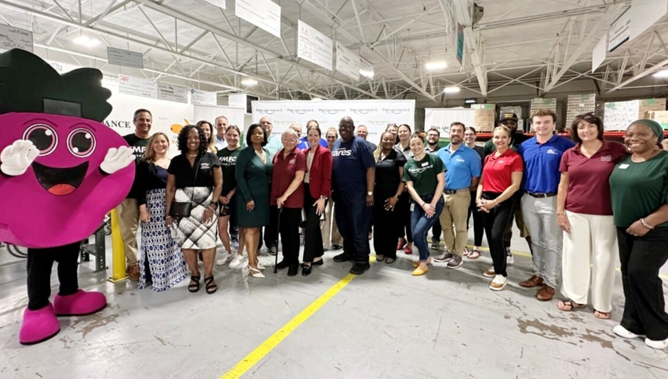 Group photo of credit union representatives with hunger relief agency mascot.