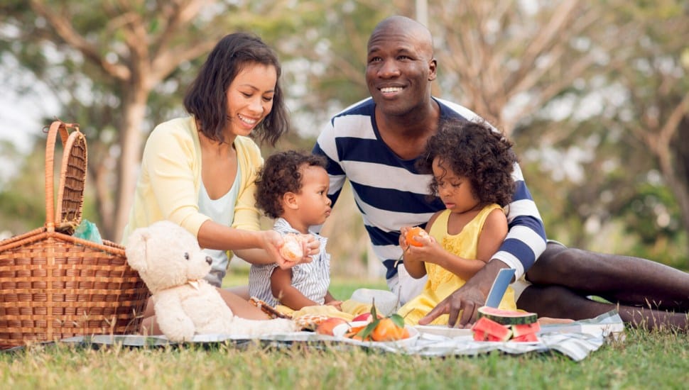A woman, man and two children enjoy an outside picnic.