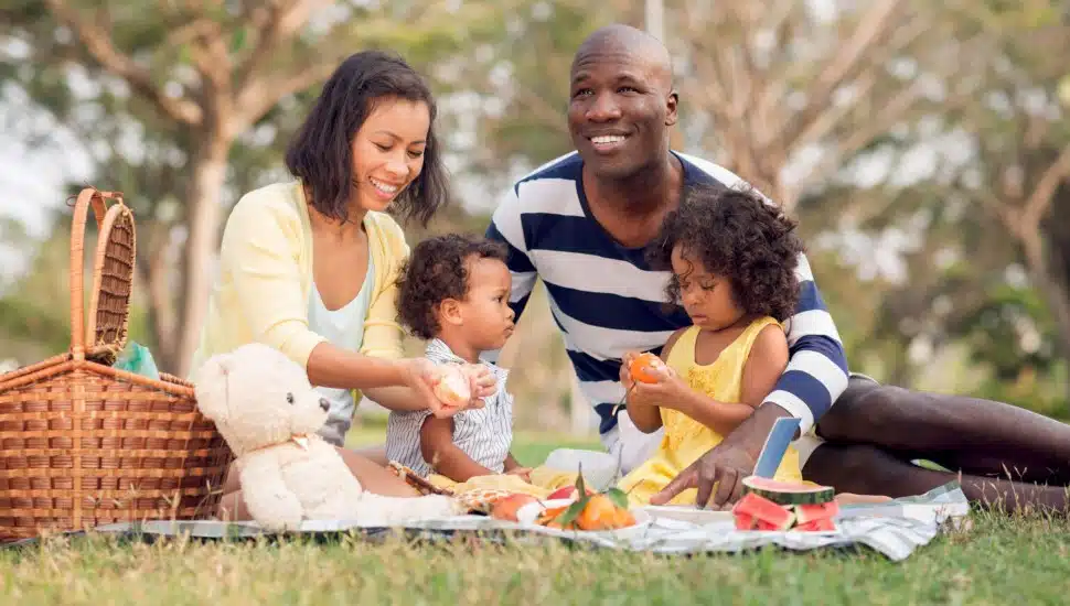 A woman, man and two children enjoy an outside picnic.