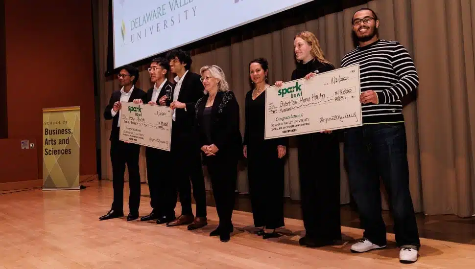 Student entrepreneurs pose for picture on stage with giant check.