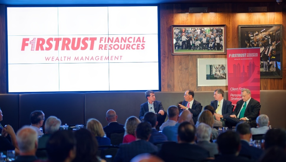 Panelists discuss market on stage in front of audience.