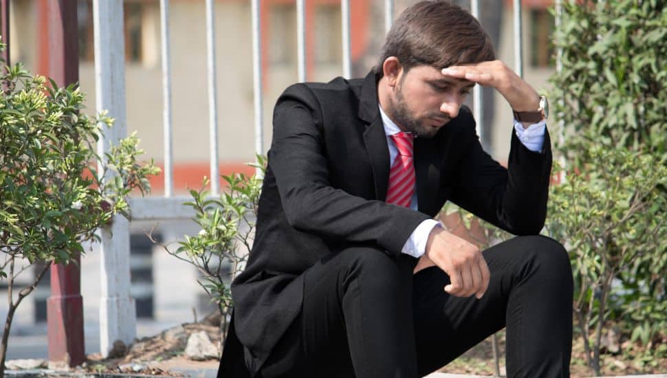 Man upset sitting on a curb.