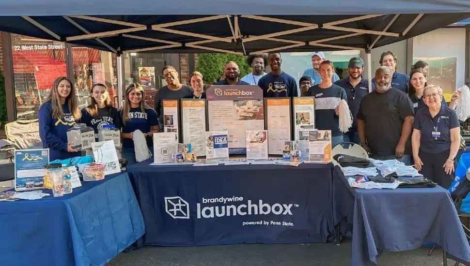 Members of the Penn State Alumni Society standing behind tables promoting the Brandywine Launchbox at Media Borough’s “Dining Under the Stars.”