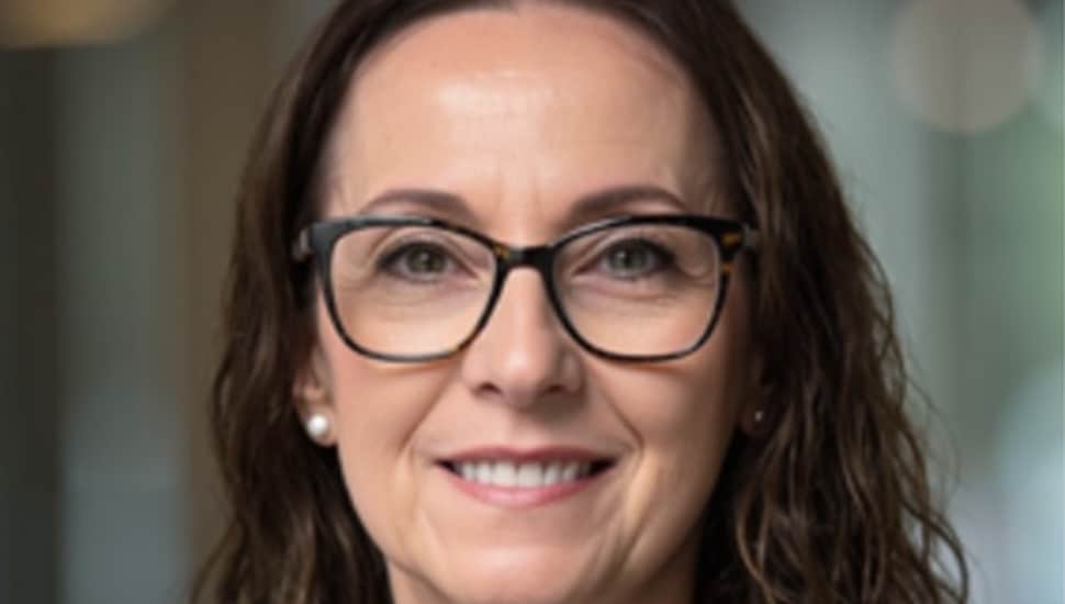 Headshot of middle-aged woman with dark hair and glasses.