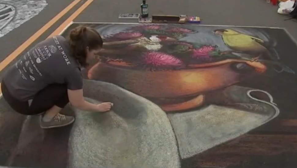 An artist works on a chalk art project in Chester.