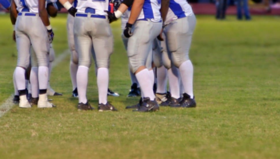 high school football players huddle on the field.