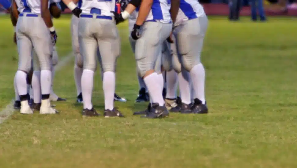 high school football players huddle on the field.