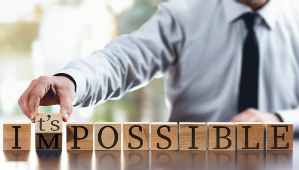 A businessman with wooden blocks changes the "impossible" wording to "It's possible."