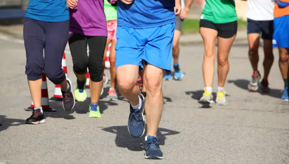 A group of people, seen from mid-waist down, participating in a run.