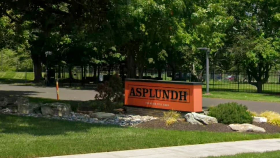 Asplundh Tree Experts headquarters with a sign, a tree and some landscaping.