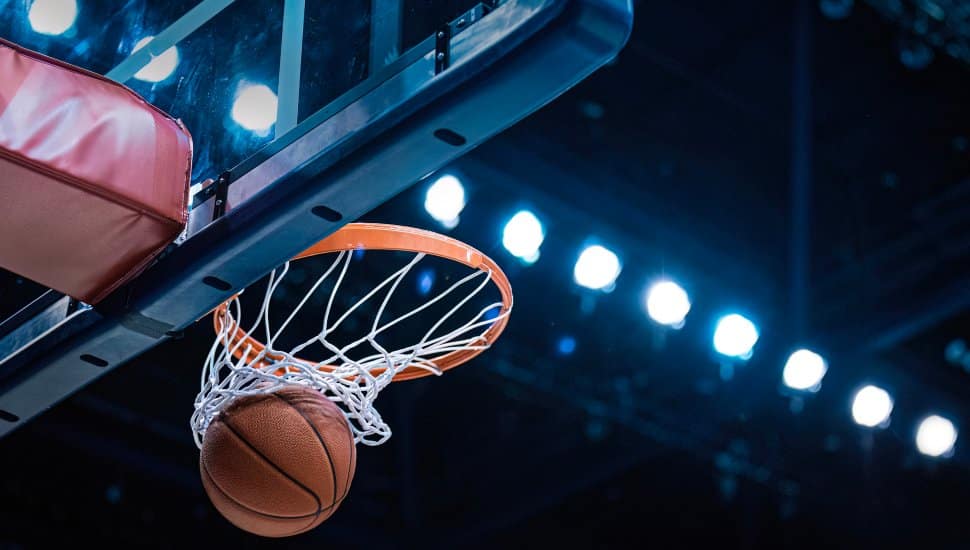 A basketball passes through an indoor basketball net.