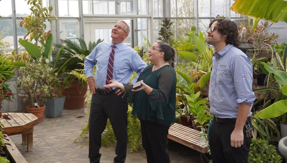 State official visits greenhouse on college campus.