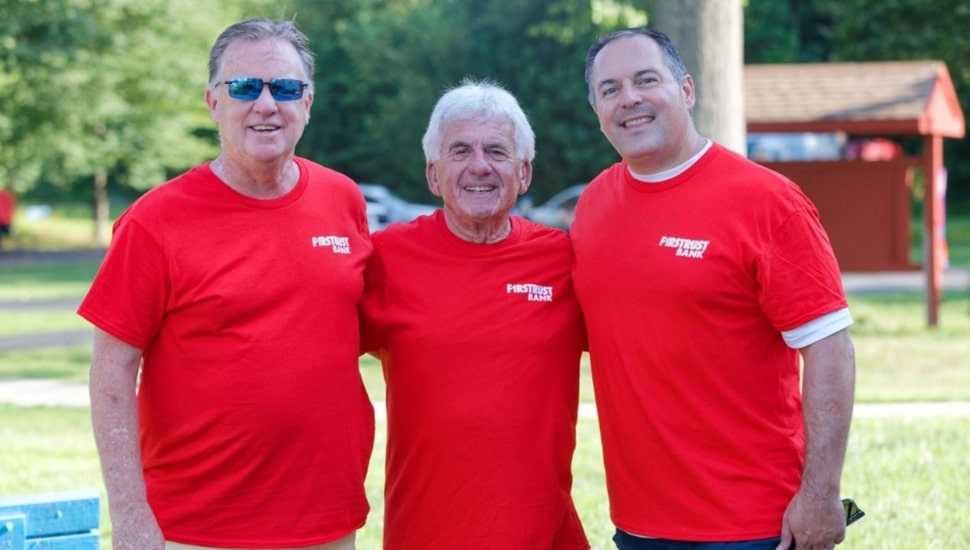 Three male bank employees in red t-shirts.