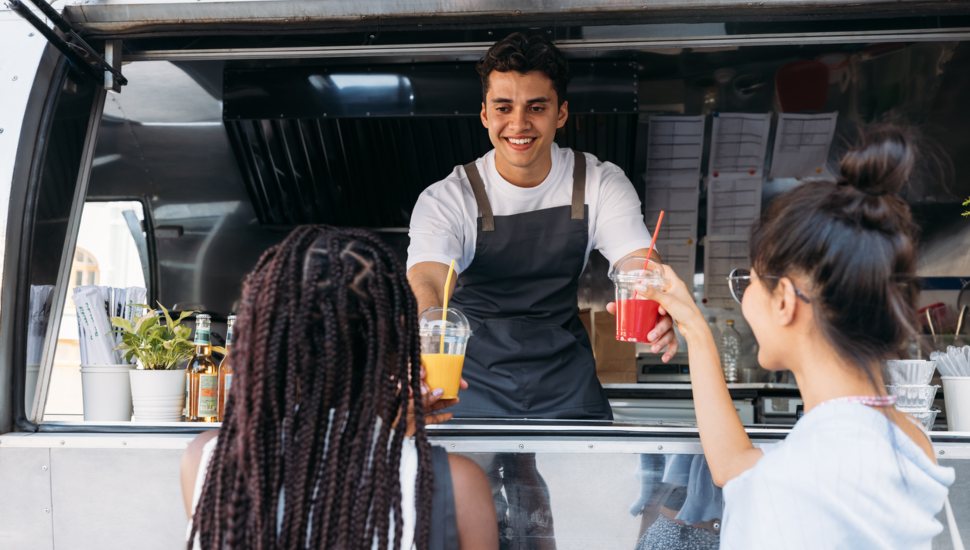 A food truck worker serves a customer.