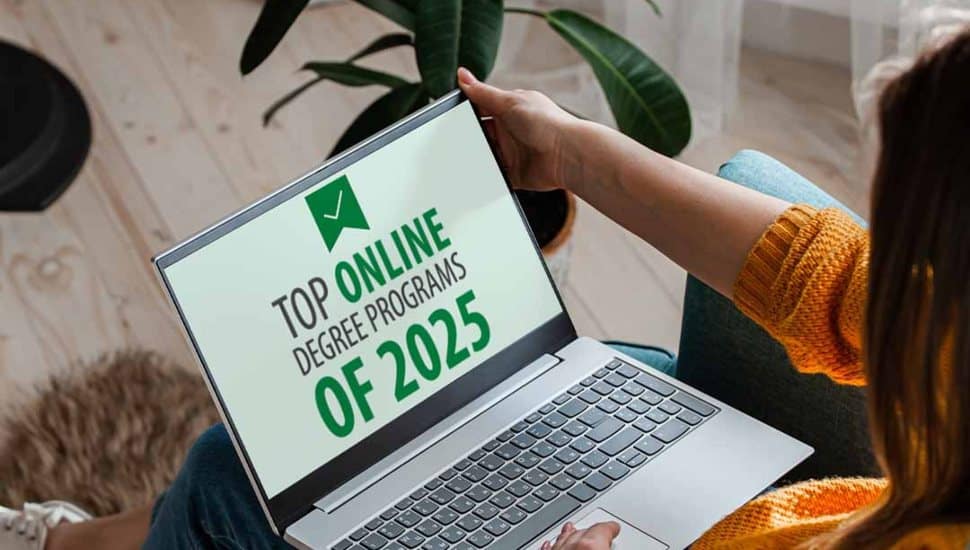 A student views a laptop screen displaying the text “Top Online Degree Programs of 2025,” highlighting Wilmington University’s Forbes Advisor recognition for its leading online programs.