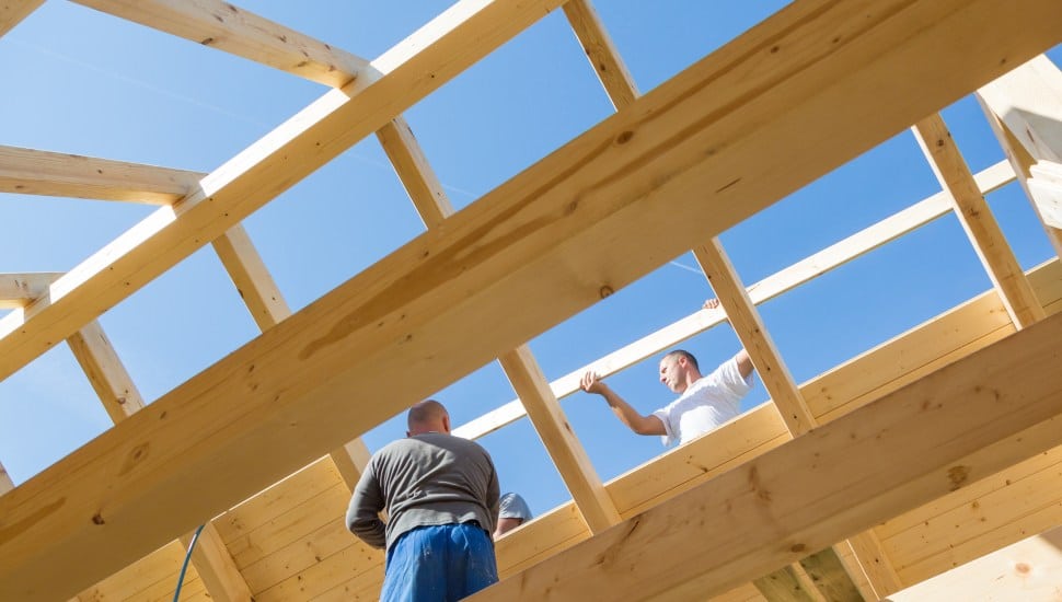 Workers at the frame of a home under construction.