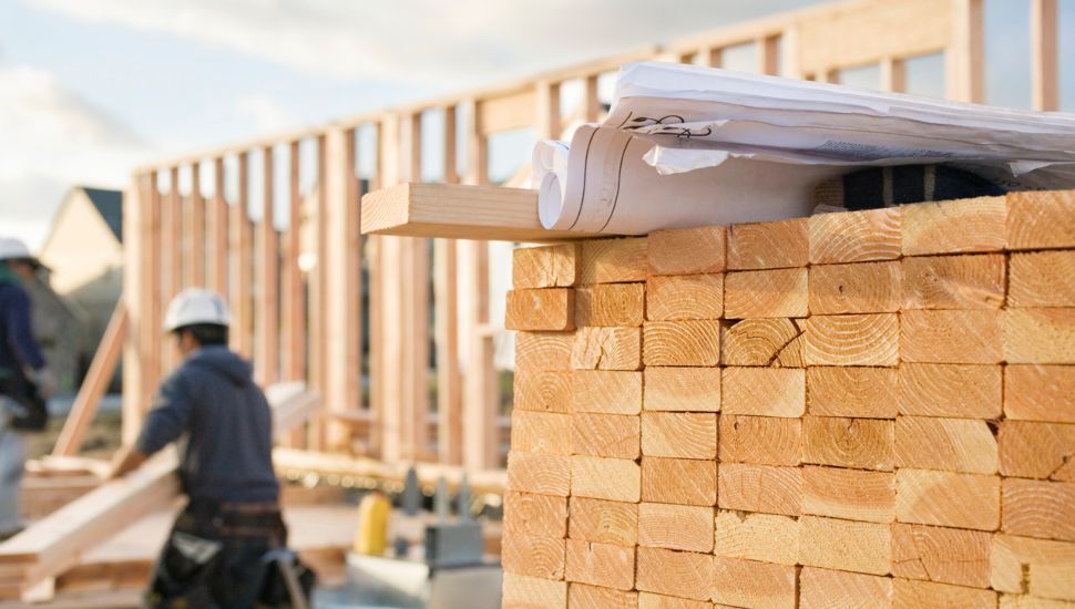 Homebuilders working with lumber at the framework of a home under construction.