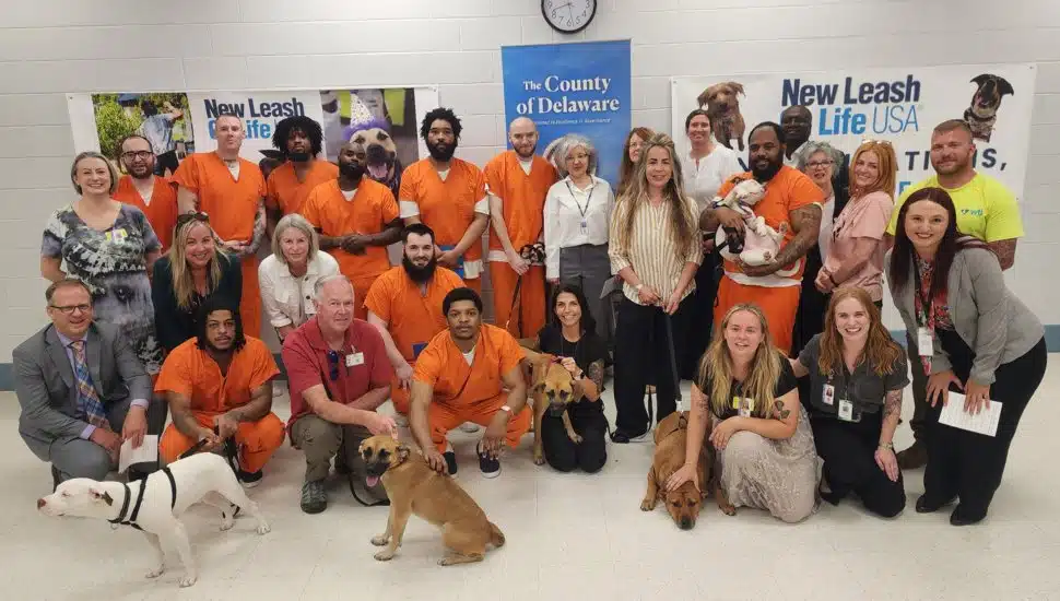 A group photo of the organizers and graduates, along with their dogs, of the 2025 New Leash on Life program at the George W. Hill Correctional Facility in Thornton.