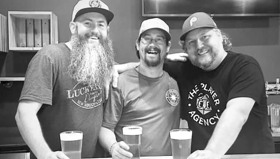 Three happy men pose for a photo at RiverTide Brewery.