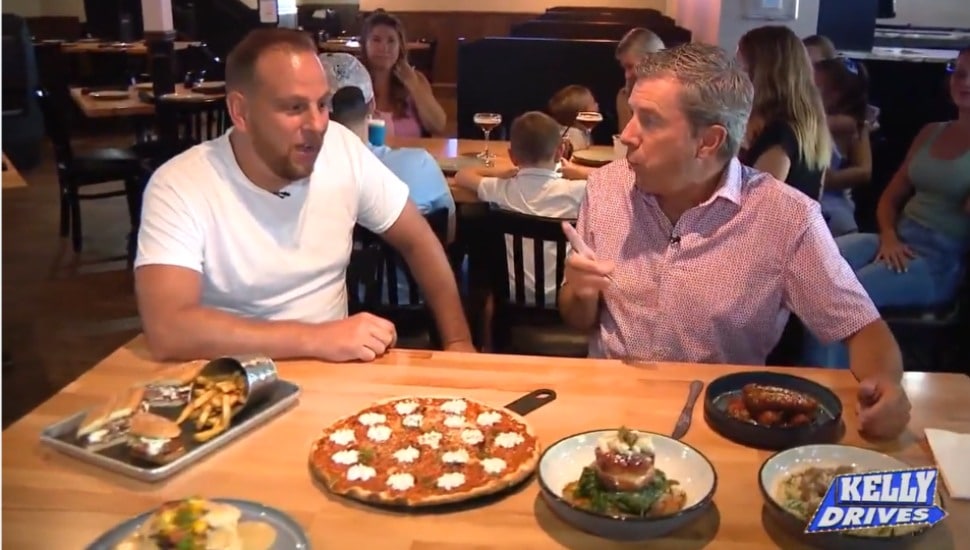 CJ, owner of Santino's Tap & Table in Ridley shows some of Santino’s entrees to Bob Kelly of Fox 29. Image via Fox 29.