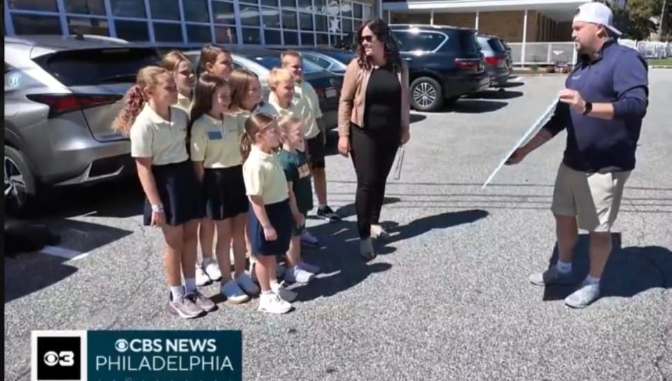 Vince Sculli, owner of Choice Sports Cards in Aston, presents a symbolic check for $8,500 to students at St. Francis of Assisi School in Springfield to help with rebuilding costs.