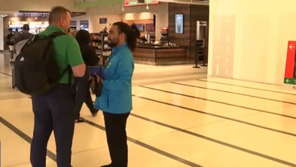 Austin Brito-Quinones, part of the airport’s new customer care team, speaks with a passenger.