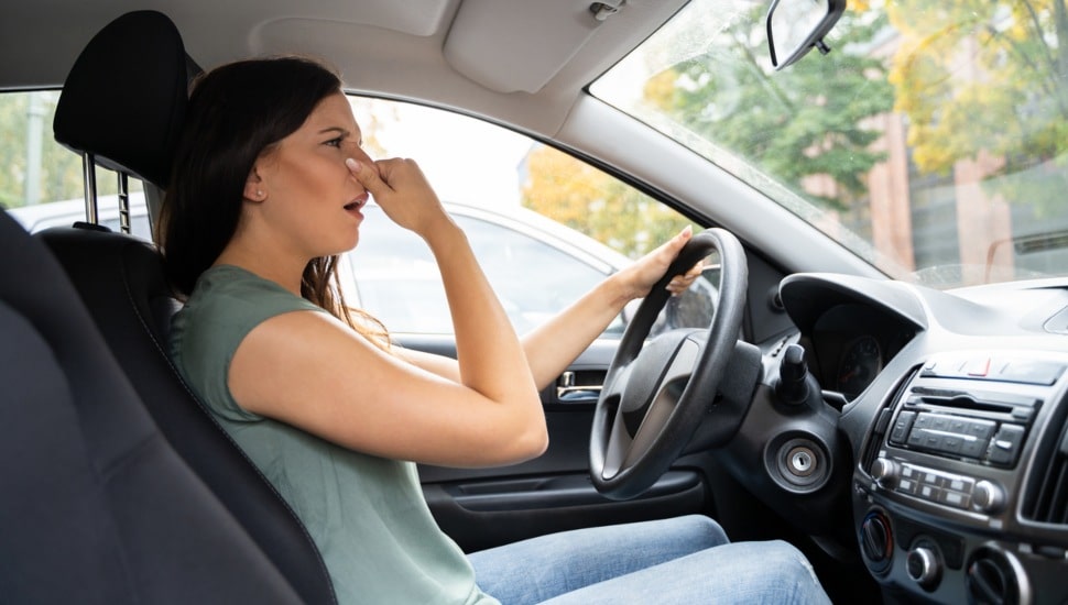 Woman driving in her car smells something bad.