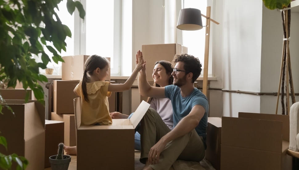 A mom, dad and a daughter with boxes moving into an apartment.
