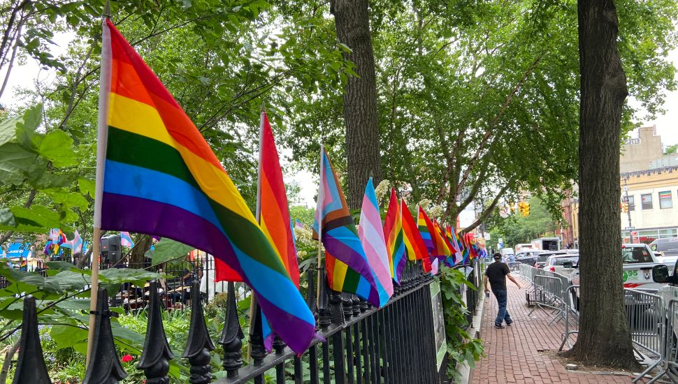 Pride flags running along an iron fence.