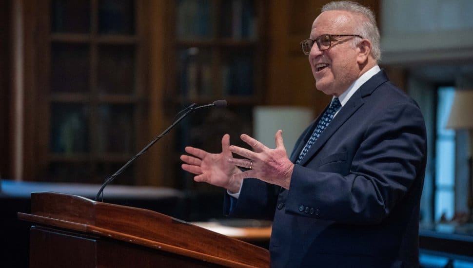 Former Pennsylvania State Senator Andrew Dinniman speaking at a podium during a West Chester University event, addressing the audience with an engaging gesture.