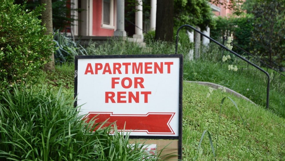 An apartment for rent sign on a front lawn.
