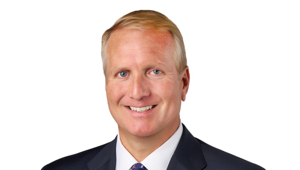 Headshot of middle-aged male banking executive in dark suit and white shirt.