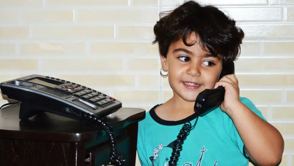 A little girl talks on a landline home phone.