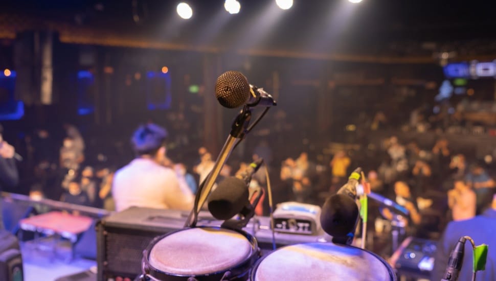 An empty stage in a bar with instruments and a microphone.