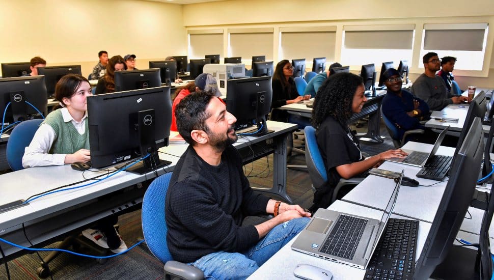 Students in a computer lab at Delaware County Community College participate in an AI-focused class, working on desktops and laptops during an interactive lesson.