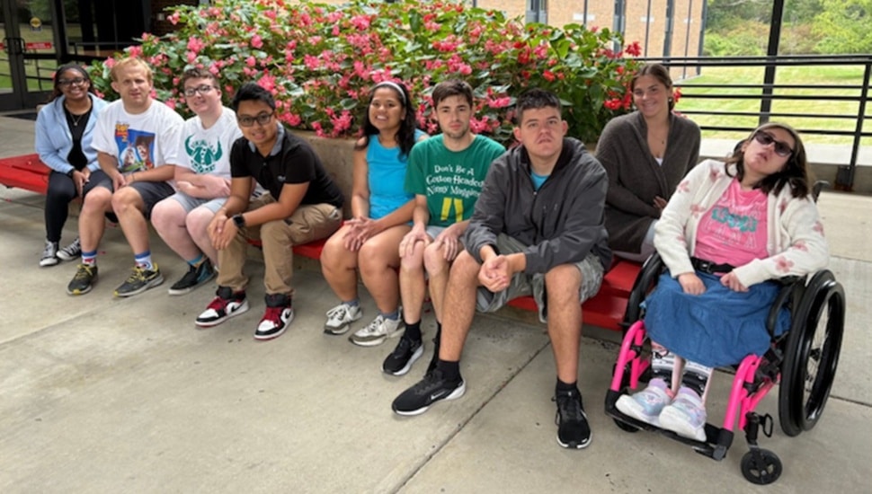 Students with intellectual disabilities sit on college campus.