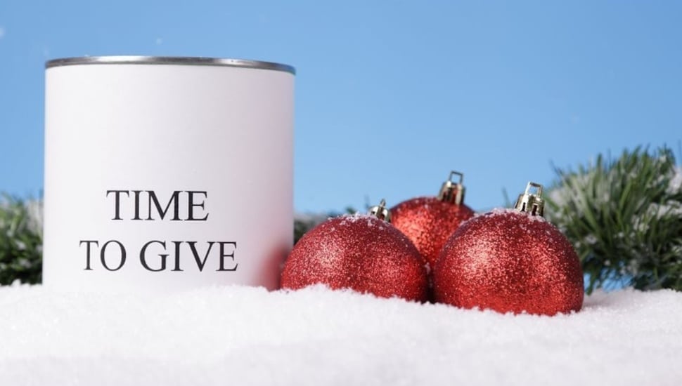 Candle with the words Time to Give with Christmas ornaments.