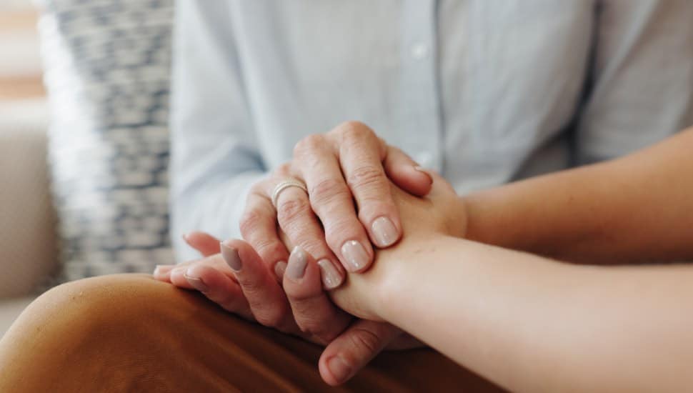 Hands hold hands that are grieving.