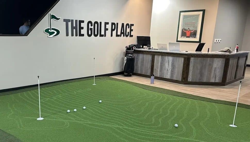 An inside look at the Golf Place with a putting green and a reception desk.