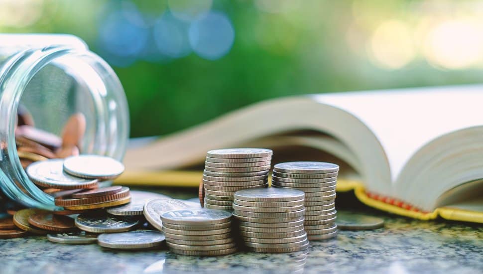 A bottle turned sideways with spilled coins and an open book.