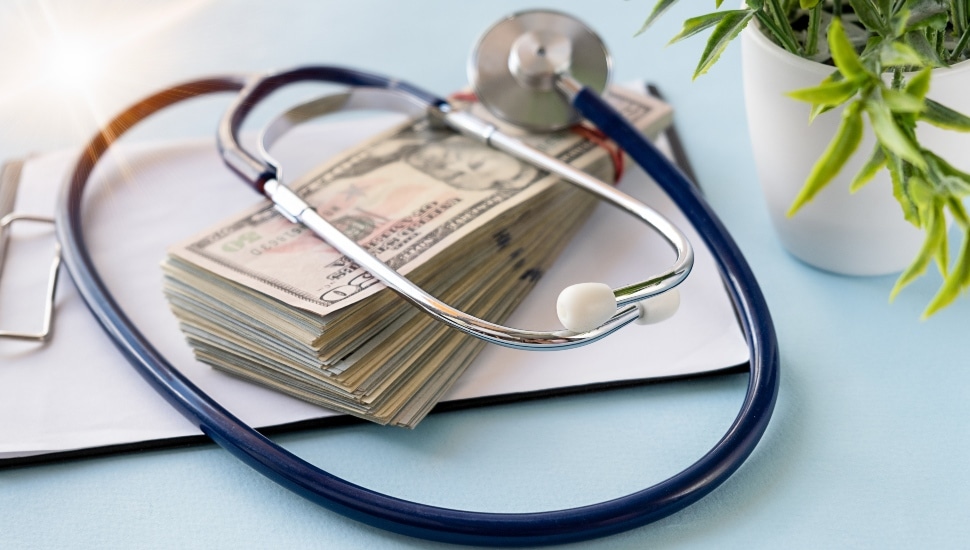 A doctor's stethoscope on top of a pile of cash.