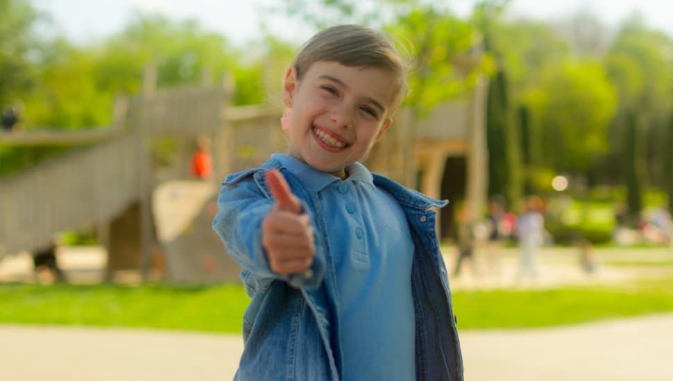 A little boy gives a thumbs up.