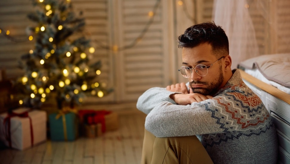 Pensive man feeling sad while being alone at home for Christmas.