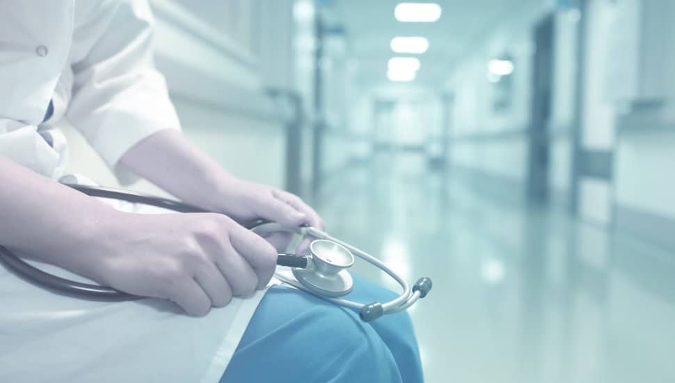 A medical professional sits in a hospital hallway.